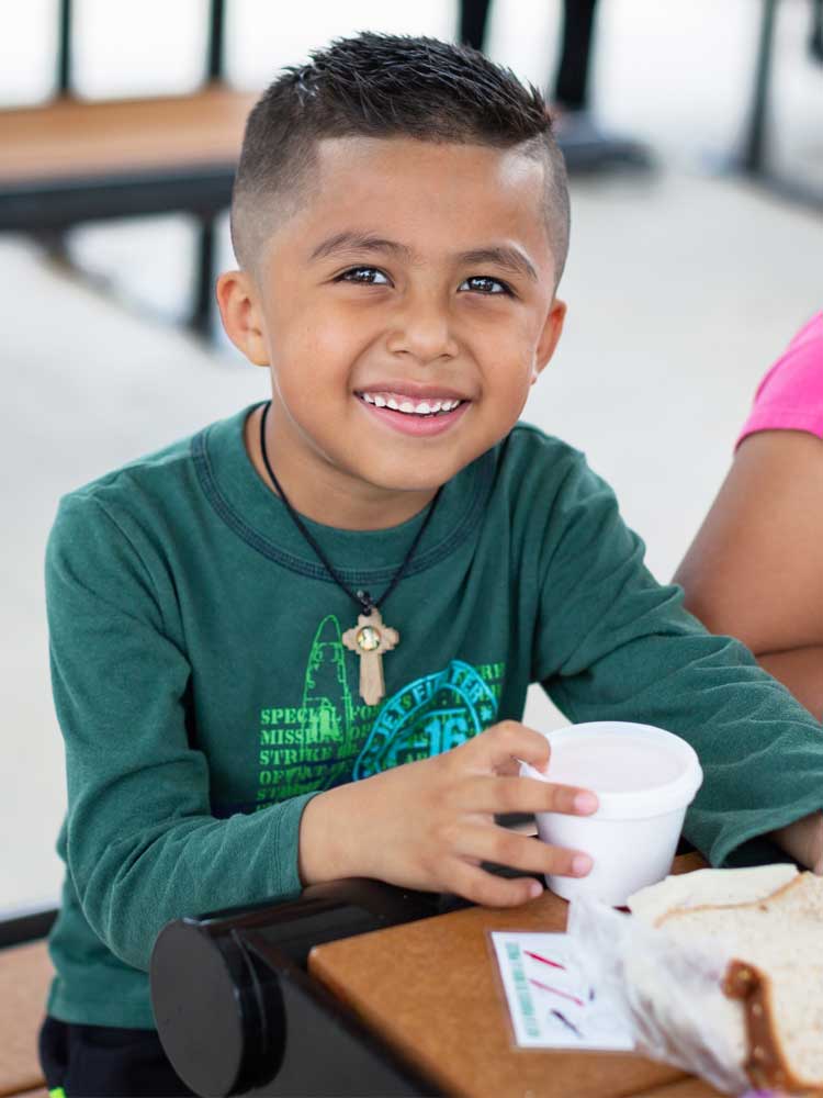 A happy young boy in Hawaii with a nutritious meal provided by the Food for Keiki initiative.